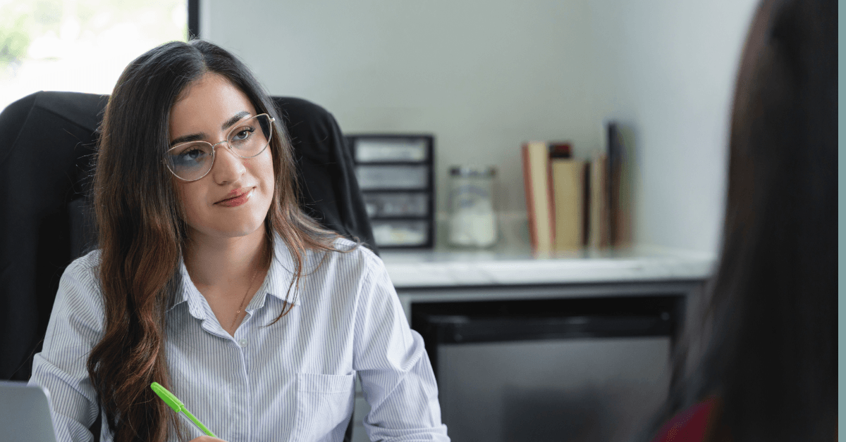 Woman siting in an office, listening attentively.